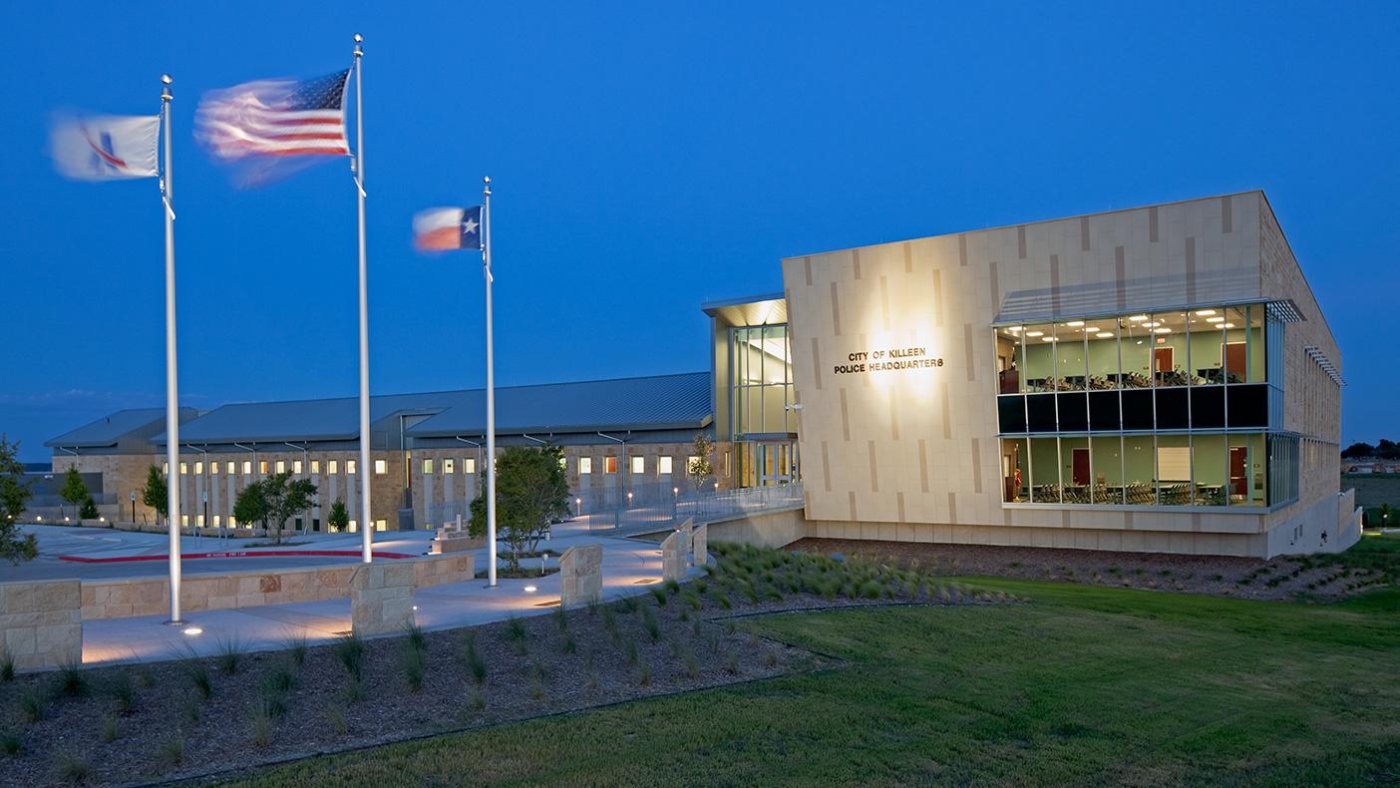 City of Killeen Police Headquarters at dusk, with the United States, Texas, and city flags flying out front
